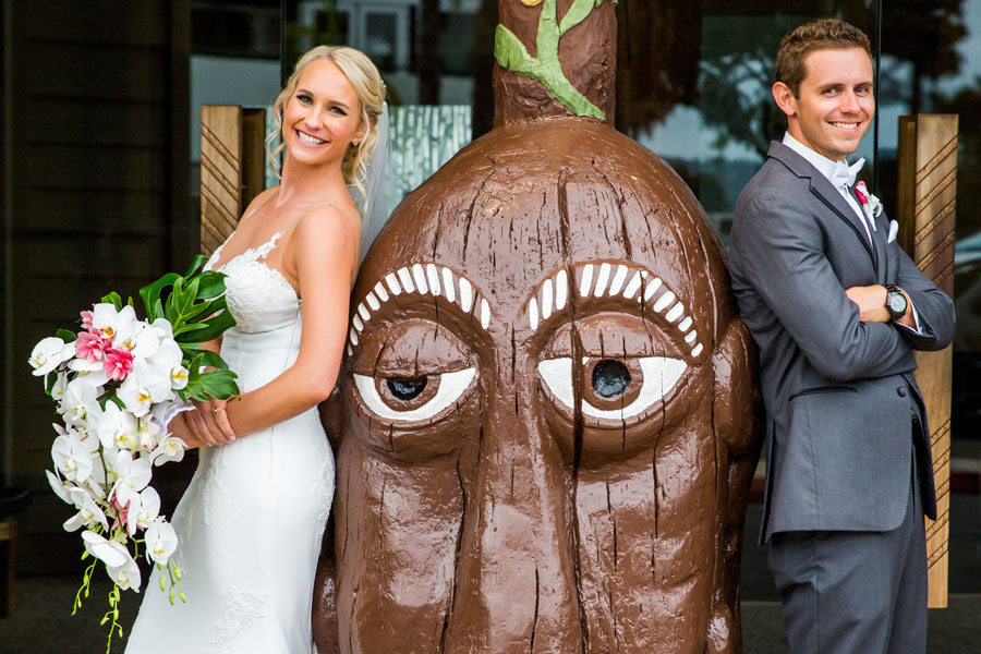 A happy couple after their wedding with a tiki head