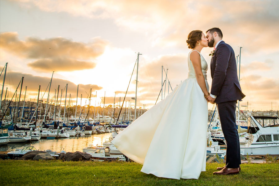 bride and groom near the water and boats