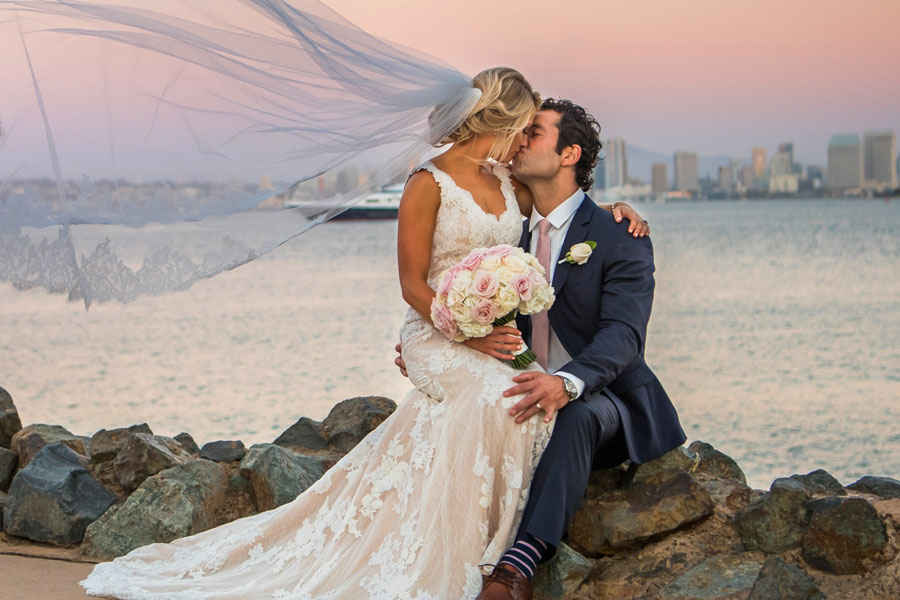 A couple kissing near the water on their wedding day