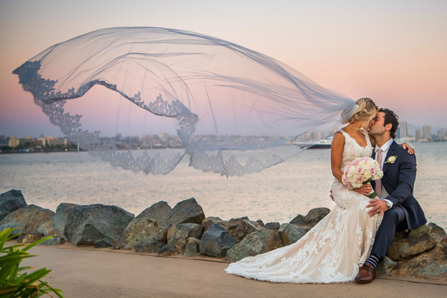 A couple kissing near the water on their wedding day